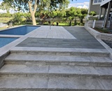 Natural stone terrace steps leading to a custom in-ground pool at a Long Lake residence