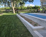 Raised stone landscape bed and pool terrace during a Long Lake backyard transformation