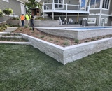 Custom stone retaining wall and landscape bed surrounding a Long Lake pool patio