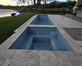 Custom in-ground pool with natural stone coping overlooking Long Lake