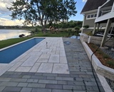 Spacious stone terrace and pool deck designed for outdoor entertaining in Long Lake