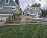 Front view of a completed Long Lake landscape project featuring a custom pool and stone terrace
