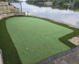 Waterfront putting green surrounded by stone hardscaping in Champlin, MN